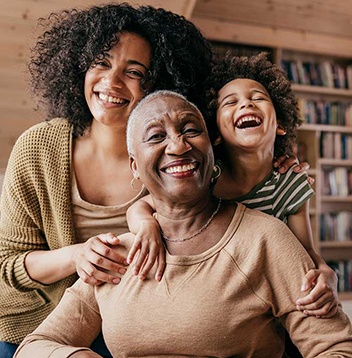 A grandmother, mother, and a child laughing together and smiling